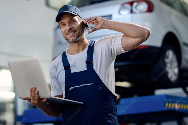 happy-mechanic-using-computer-talking-cell-phone-auto-repair-shop_637285-9762
