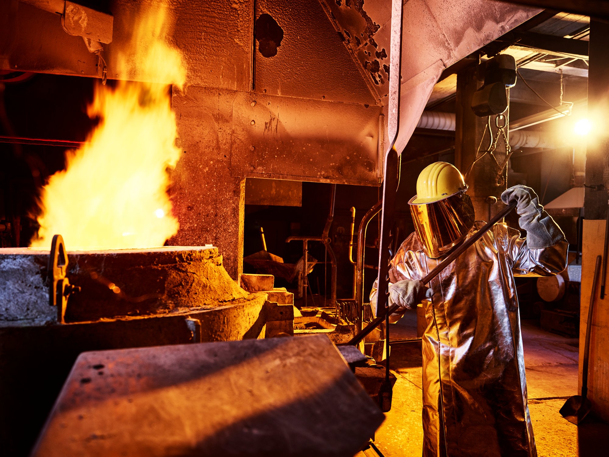 worker-holding-metal-rod-in-furnace-at-foundry-2022-12-16-22-05-31-utc
